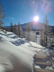 a snow covered slope with the sun shining on a mountain at Chalet Marano Restaurant & Spa in Isola 2000