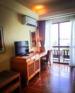 een kamer met een bureau, een televisie en een balkon bij Langkawi Lagoon Resort Seaview in Pantai Cenang