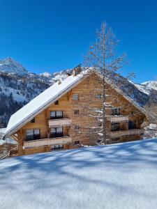 une cabane en rondins dans la neige avec un arbre dans l'établissement Chalet Marano Restaurant & Spa, à Isola 2000