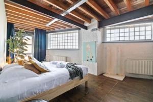 a bedroom with a large bed in a room with windows at Industrial loft near the center of Ghent in Ghent