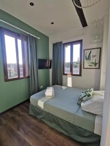 a bedroom with two beds with green walls and windows at La Terrasse suspendue des Arènes - Une Nuit à Nîmes in Nîmes