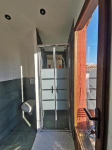 una puerta de cristal que conduce a un baño con aseo en La Terrasse suspendue des Arènes - Une Nuit à Nîmes, en Nimes