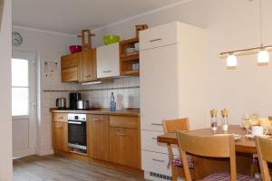 a kitchen with a dining table and a kitchen with white cabinets at Hus-Hiddensee-Eckhaus-A in Vitte