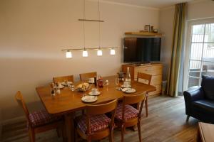 une salle à manger avec une table, des chaises et une télévision dans l'établissement Hus-Hiddensee-Eckhaus-A, à Vitte