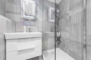 een badkamer met een witte wastafel en een douche bij Majestic 2 BR in Knightsbridge HydePark KB70 in Londen