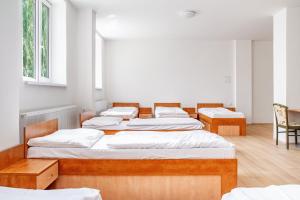 four beds in a room with white walls and wooden floors at Hostel Beskydy in Rožnov pod Radhoštěm