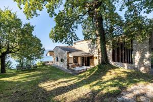 uma velha casa de pedra com uma árvore no quintal em Villa Franca San Zeno em San Zeno di Montagna