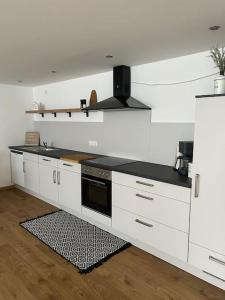 uma cozinha com armários brancos e um balcão preto em „Main“ Zuhause em Kleinheubach