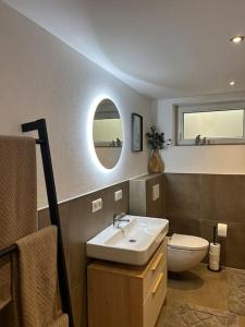 a bathroom with a sink and a toilet and a mirror at „Main“ Zuhause in Kleinheubach
