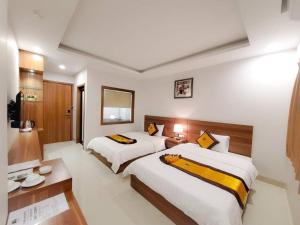 a hotel room with two beds and a desk at Tuấn Linh Hotel in Ha Long