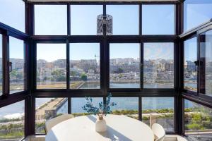 a room with a table and a bunch of windows at Salina. Peaceful 2 bedroom flat in Naxxar