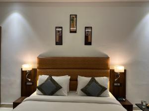 a bedroom with a bed with two lights on the wall at Hotel Kalawati Palace in Varanasi