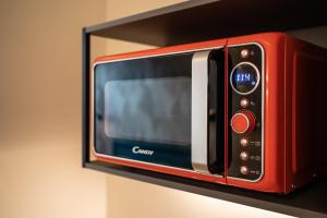 a red microwave on a shelf on a wall at The Place - Only Self Check-in - No Reception in Trento