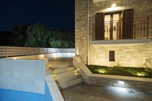 a house with stairs leading to a swimming pool at night at Aelia Sivota in Syvota