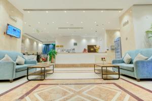 Hayah Diamond Hotel في المدينة المنورة: غرفة انتظار مع اثنين من الأرائك الزرقاء وطاولتين