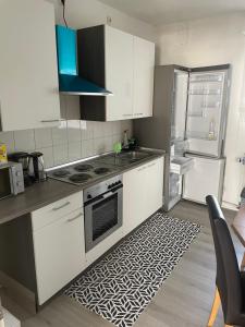 eine Küche mit weißen Schränken, einem Herd und einem Kühlschrank in der Unterkunft Ferien - Wohnung In Kassel Waldau Zentral in Kassel