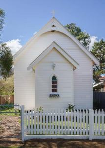 a small white church with a white fence at St Aidan's - Converted Church in Mudgee