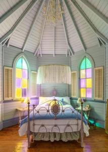 a bedroom with a bed in a room with windows at St Aidan's - Converted Church in Mudgee
