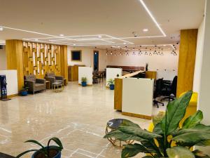 a lobby with chairs and plants in a building at Hotel Plaza Airport Zone in Shamshabad