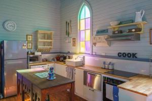 a kitchen with a refrigerator and a table in it at St Aidan's - Converted Church in Mudgee