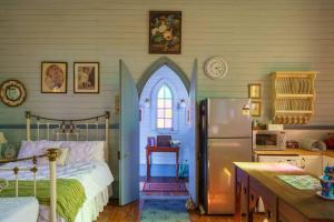 a kitchen with a bed and a refrigerator in a room at St Aidan's - Converted Church in Mudgee