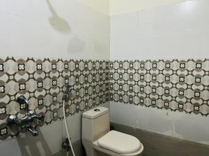 a bathroom with a toilet and a wallpaper with faces on it at Hotel Plaza Airport Zone in Shamshabad