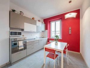 una cucina con tavolo bianco e parete rossa di Appartamento Rubino a Gorizia