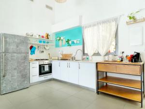 a kitchen with white cabinets and a sink and a stove at Roberta's Apt Flea Market/Patio/ By the beach in Tel Aviv