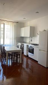 uma cozinha com mesa, cadeiras e electrodomésticos brancos em Appartamento zona centro Savona con due camere em Savona