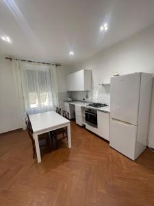 uma cozinha com uma mesa e um frigorífico branco em Appartamento zona centro Savona con due camere em Savona