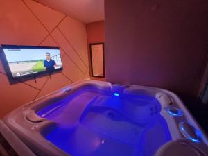 een bad met een tv in de kamer bij Les Spa de Venus suites avec jacuzzi spa privatif in Charavines