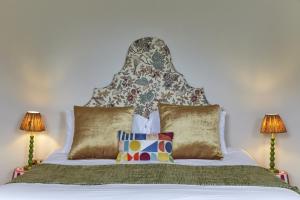 a bed with a headboard with pillows and two lamps at 81 Promenade Studios in Cheltenham