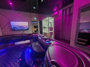ein lila Zimmer mit Whirlpool-Badewanne und lila Lichtern in der Unterkunft Les Spa de Venus suites avec jacuzzi spa privatif in Charavines