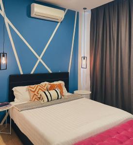 a bedroom with a bed with a blue wall at Pleasant Amenities at ITCC Manhattan Suites in Penampang