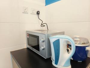 a microwave sitting on a counter next to a blender at Pleasant Amenities at ITCC Manhattan Suites in Penampang