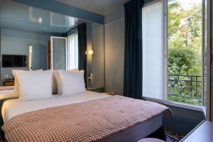 a bedroom with a bed and a large window at Hôtel La Conversation in Paris