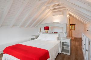 a bedroom with a white bed with a red blanket at Villa Do Mar in Arco da Calheta