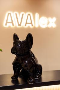 una statua di un cane seduto su uno scaffale di fronte a un cartello di Hotel AVAlex a Berlino