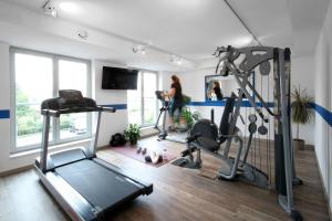 ein Zimmer mit einem Fitnessraum mit zwei Laufbändern und einer Frau in der Unterkunft Best Western Hotel Halle-Merseburg in Merseburg