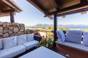 a porch with a couch and a stone wall at PORTO ROTONDO SPLENDIDO APPARTAMENTO VISTA MARE in Porto Rotondo