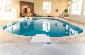 una grande piscina in una grande stanza con sedia bianca di مزرعة واستراحة الفقع a Al Faq‘