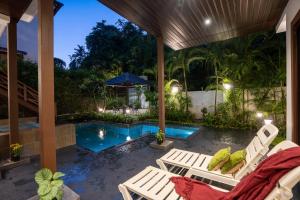 a patio with chairs and a swimming pool at night at Elivaas Indah Luxe 4BHK Villa with Pvt Pool, Moira in Old Goa