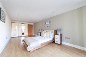a white bedroom with a large bed and wooden floors at The Greenwich Collection in London