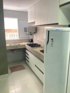 La cuisine est équipée de placards blancs et d'un réfrigérateur blanc. dans l'établissement Jr FLATS, à João Pessoa