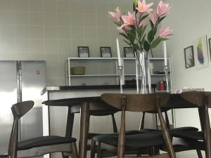 una mesa de comedor con un jarrón de flores rosas. en Homestay Fe-feeling Artis with 4 Bedrooms, en Rawang