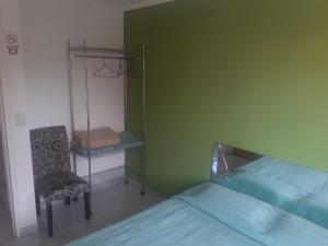 Habitación verde con cama y silla en NUESTRO MUNDO TRELEW en Trelew