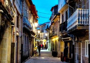 un callejón con gente caminando por una calle por la noche en Holibai, Vermello, Un rincón con encanto cerca de la playa, en Baiona