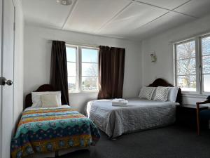 1 dormitorio con 2 camas y 2 ventanas en Rainbow Motel, en Tauranga