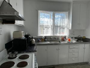 a white kitchen with a stove and a sink at Rainbow Motel in Tauranga