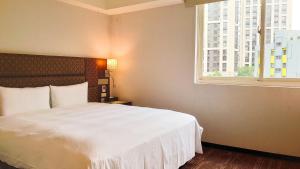 a bedroom with a white bed and a window at Hub Hotel Banqiao Branch in Taipei